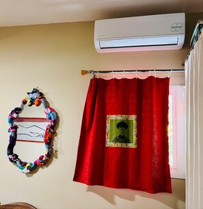 Une pièce avec un rideau rouge, un climatiseur fixé au mur et un décor circulaire aux couleurs vives.