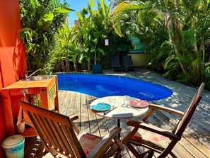 Une terrasse en bois avec une piscine, entourée d’une végétation luxuriante.