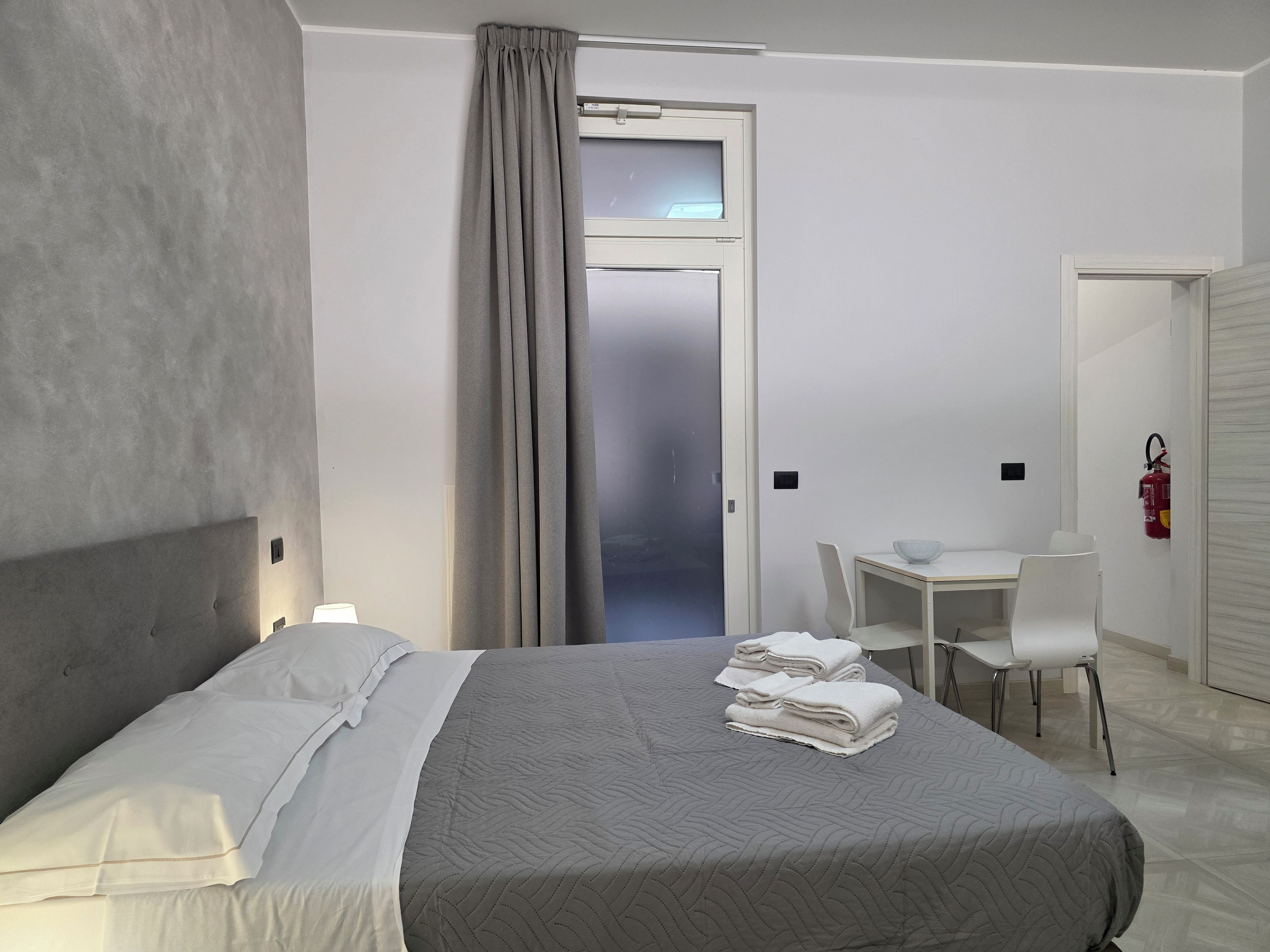Una habitación de hotel con cama, escritorio, silla y extintor.