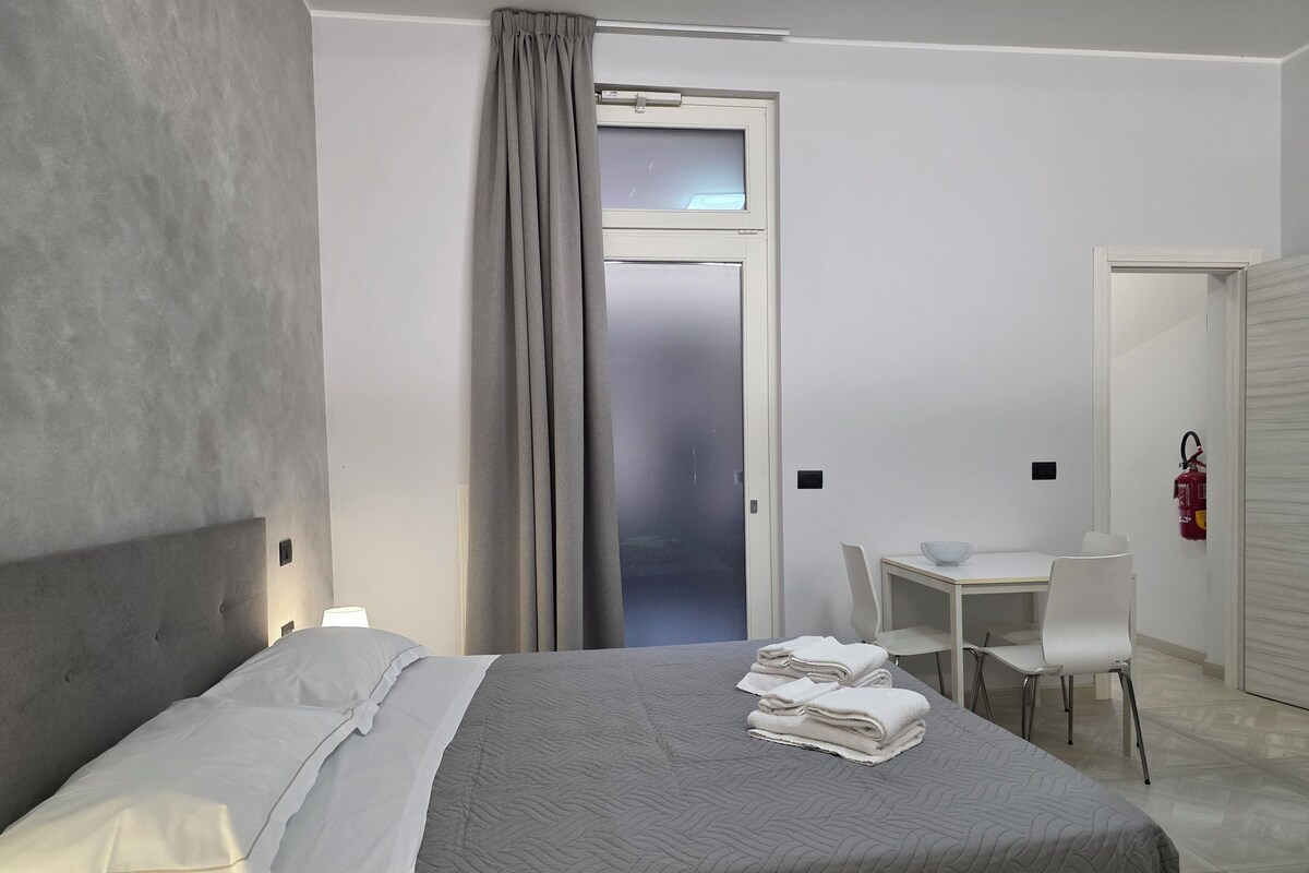 Una habitación de hotel con cama, escritorio, silla y extintor.