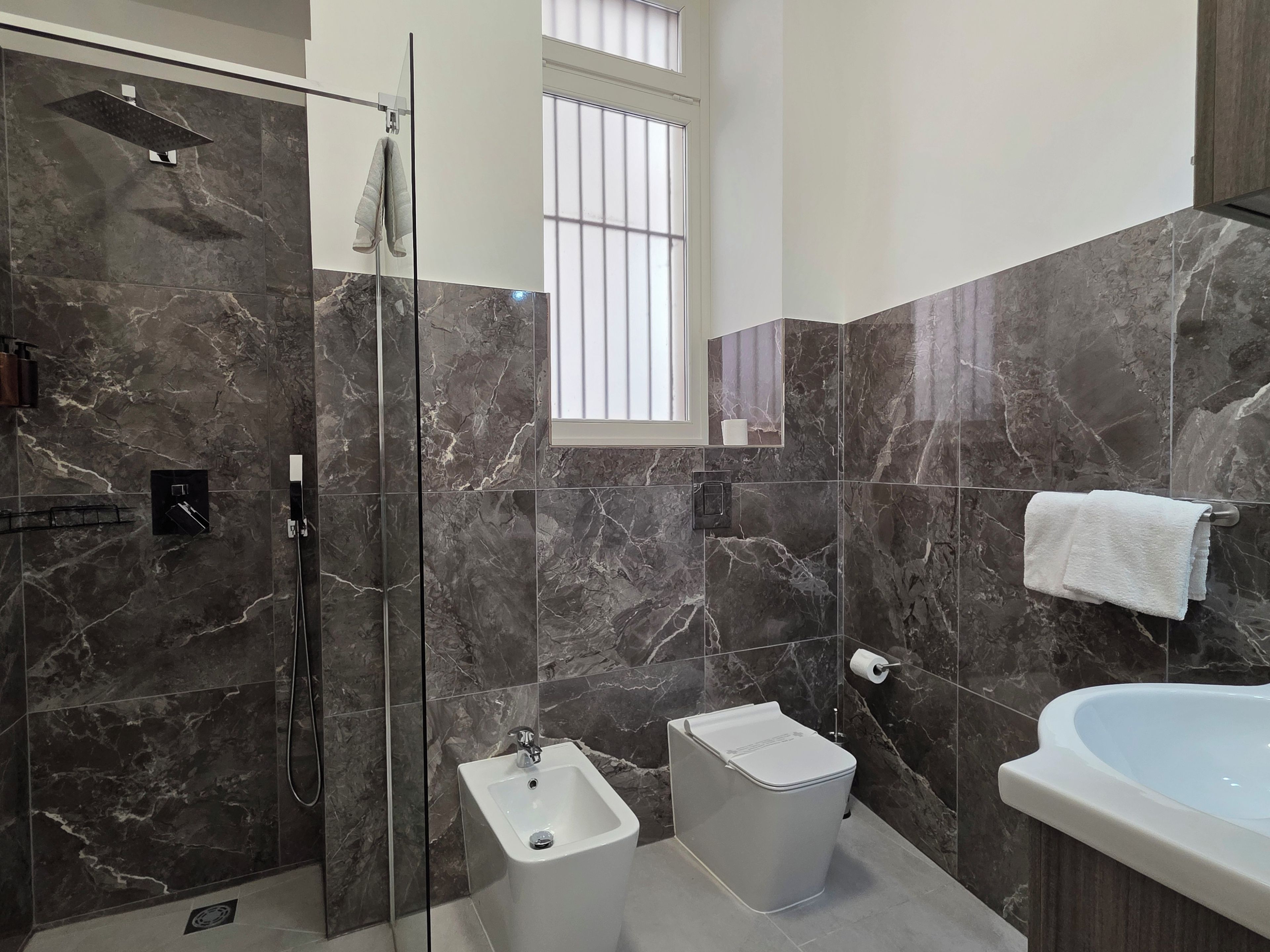 Un baño moderno con ducha acristalada, un bidé, un inodoro y una bañera.