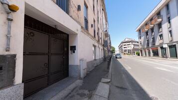 Straßenansicht mit einem Gebäude, das ein großes schwarzes Tor, einen Bürgersteig und einen strahlend blauen Himmel zeigt.