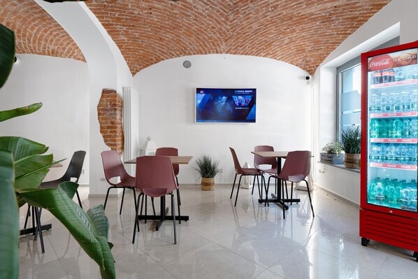 Un restaurant avec un plafond en briques, des murs blancs et un réfrigérateur rouge de la marque Coca-Cola.