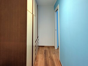 Un pasillo con piso de madera y pared azul.