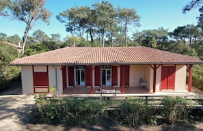 A two-story building with a tiled roof, a covered porch with red doors, and a small outdoor seating area. - New Listing (Moliets-et-Maa)