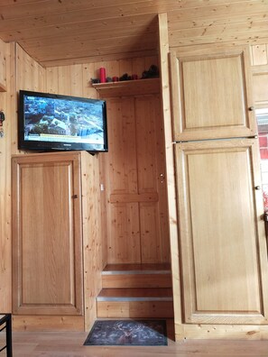Ein Holzinnenraum mit an der Wand befestigtem Fernseher, einem Holzboden und einer Tür.