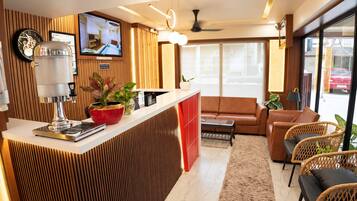 Una sala de estar moderna con una cafetera, un sofá y un televisor montado en la pared.