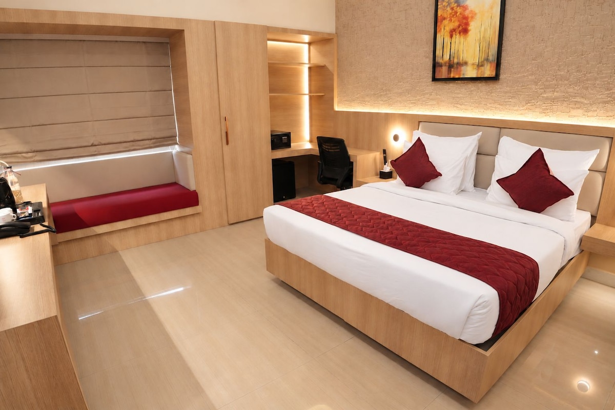 Habitació d'hotel moderna amb un llit gran, un escriptori i una cadira-banc integrada.
