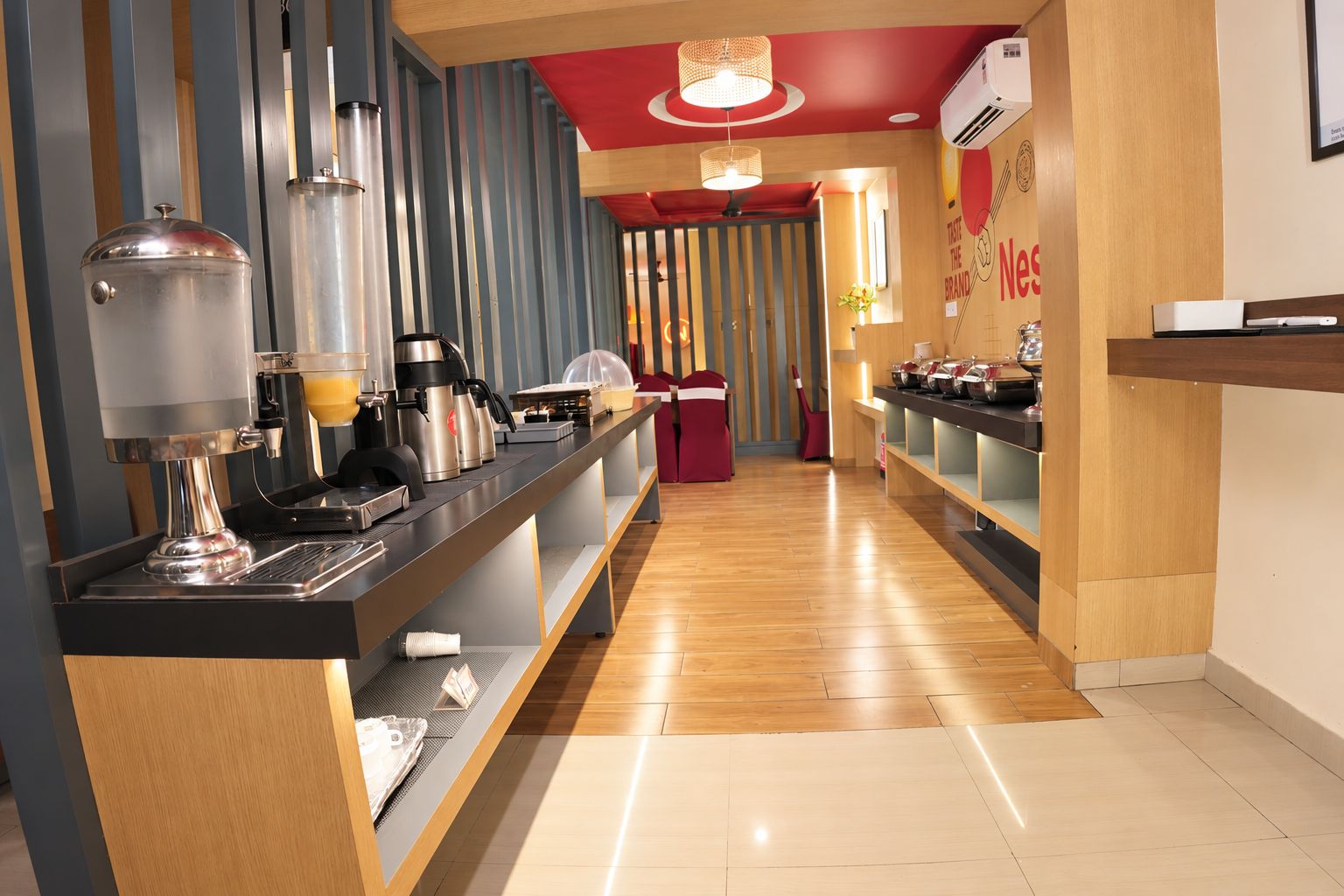 Un moderno vestíbulo de hotel con un mostrador de recepción alargado, una máquina de café y un mostrador con diversos servicios.