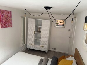 Un dormitorio con cama, armario y un cuadro en la pared.