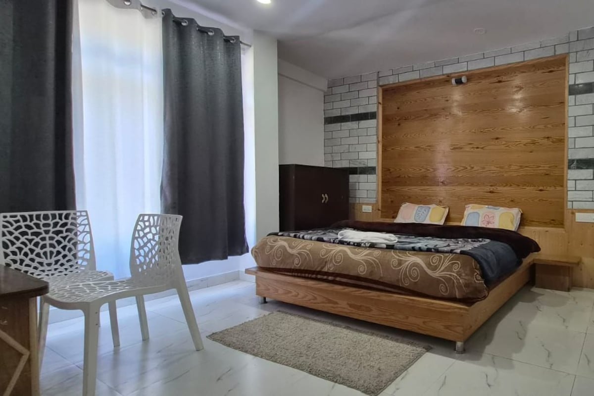 A bedroom with a bed, a wooden headboard, a white chair, and a small table.
