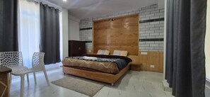 A bedroom with a bed, a wooden headboard, a white chair, and a small table. - Solang Valley Homestay (Manali)
