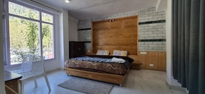 A bedroom with a bed, a window, a chair, and a wooden headboard. - Solang Valley Homestay (Manali)