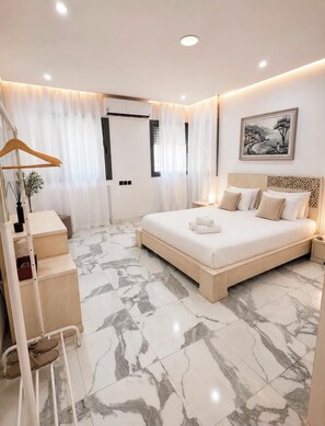 Quarto moderno com cama grande, mesa de cabeceira, guarda-roupa e luminária pendente.