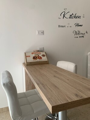 Ein Essbereich mit einem Holztisch, zwei Stühlen, einer Wand mit einer Küchenaufkleber und einer Vintage-Donutschachtel auf dem Tisch.