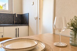 A kitchen with a dark backsplash, a sink, and cabinets. There's a glass vase with flowers on the table. - New Listing (Lucé)