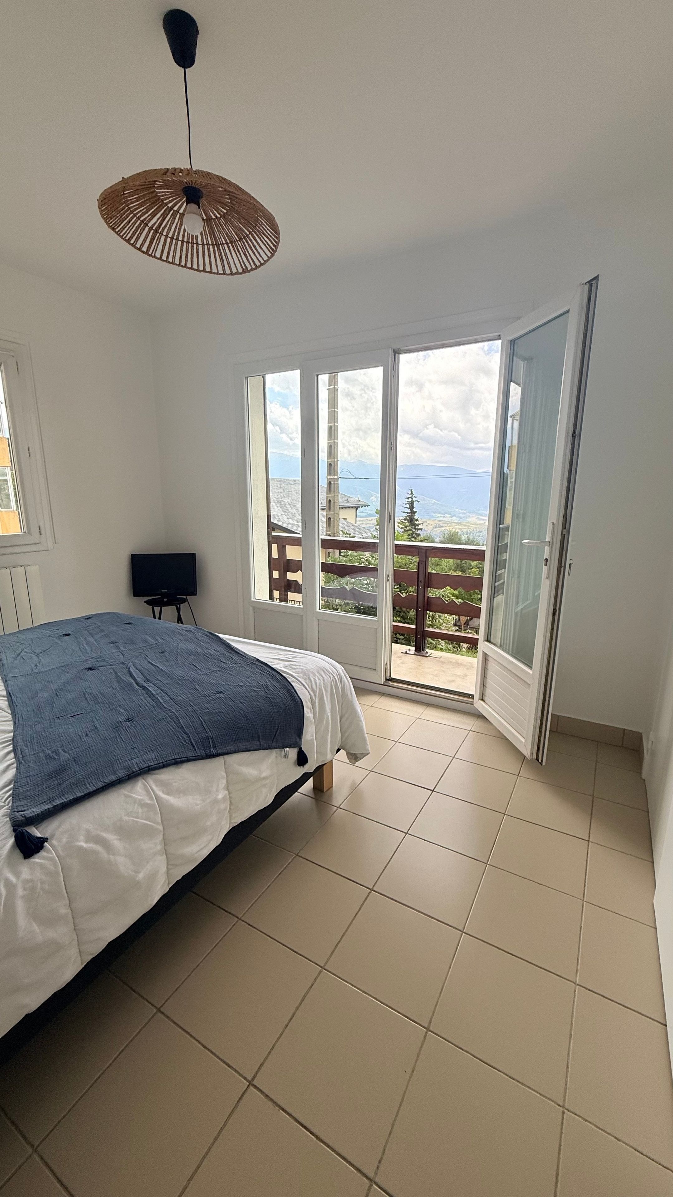 Un dormitorio con cama, televisión y balcón con vistas.