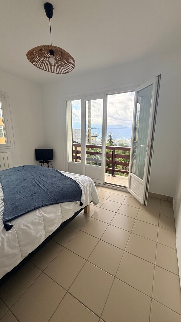 Une chambre à coucher avec un lit, une télévision et un balcon offrant une vue.