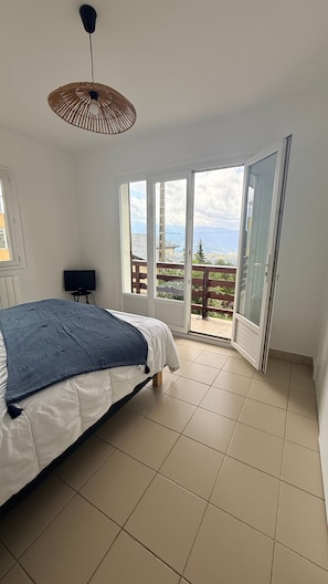 Un dormitorio con cama, televisión y balcón con vistas.