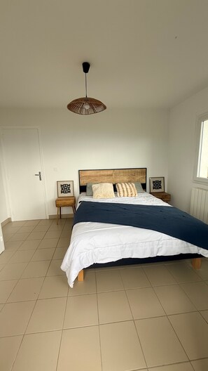 Un dormitorio con una cama, una mesita de noche, una lámpara colgante y una ventana.
