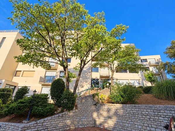A multi-story residential building with a brick staircase leading to a gated entrance. - New Listing (Royan)