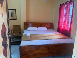 Una cama individual con cabecera de madera, una mesita de noche y una silla.