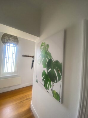 A room with a large window, a wall-mounted plant, and a wooden floor. - Brigadoon - Central Art Deco house in the heart of the CBD (Warrnambool)