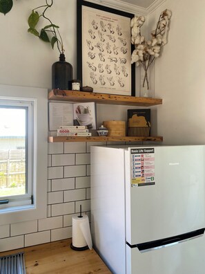 A kitchen with a white refrigerator, a framed sign language chart, and a window with a view of a fence. - Brigadoon - Central Art Deco house in the heart of the CBD (Warrnambool)