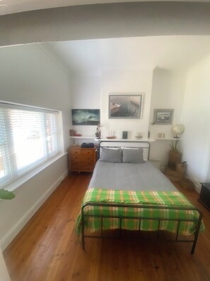 A bedroom with a bed, a dresser, a nightstand, and a window with blinds. - Brigadoon - Central Art Deco house in the heart of the CBD (Warrnambool)