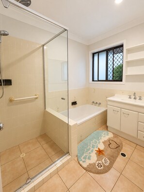 Une salle de bain avec une douche à parois de verre, une baignoire, un lavabo et une fenêtre donnant sur un beau paysage.