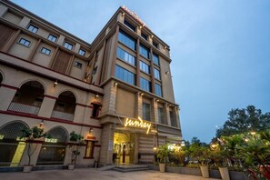 A hotel with a prominent neon sign, multiple floors, and a courtyard with potted plants. - POP 84978J Sunday Vadodara Palace Hotel (Vadodara)