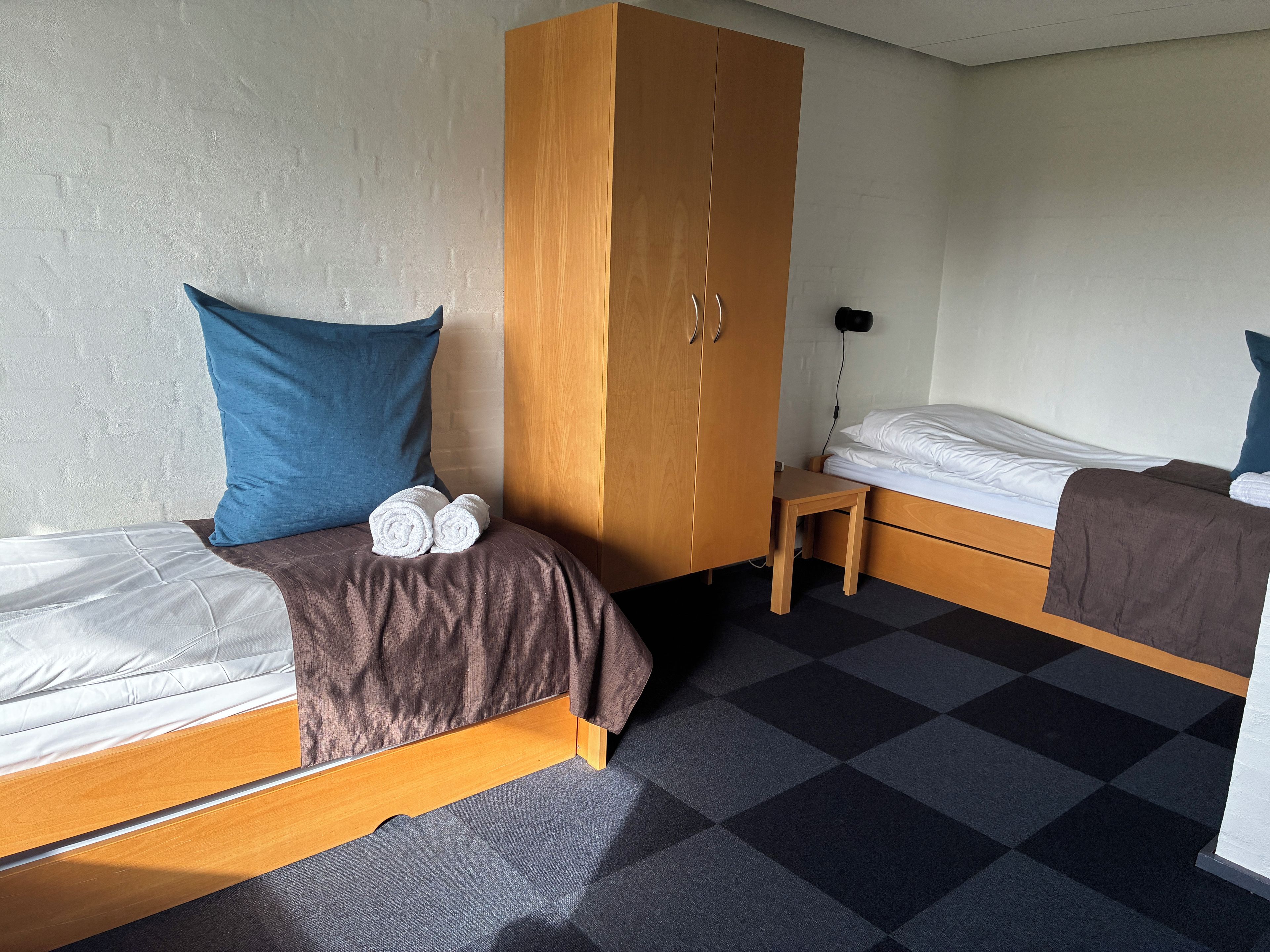 A room with two beds, a wardrobe, and a small table.