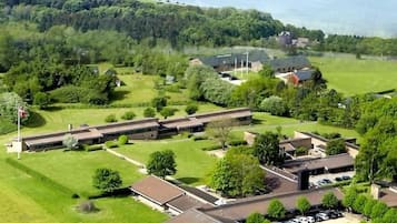 An aerial view of a campus with buildings, parking, and a bridge in the background.