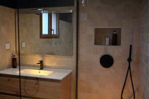 Une salle de bain équipée d’un lavabo, d’un miroir et d’un espace douche.
