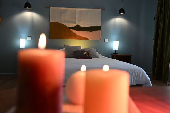 Ein Schlafzimmer mit einem Bett, Nachttischlampen, einem Gemälde und Kerzen.