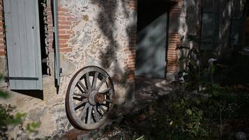 Un edificio antiguo con una rueda de madera desgastada, un muro de ladrillo y una puerta entreabierta.