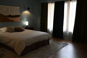 Une chambre à coucher avec un lit, une lampe de chevet et une fenêtre avec des rideaux.