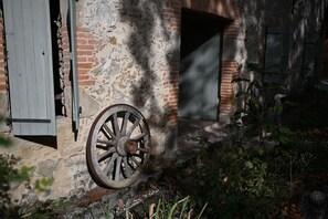 Un vieux bâtiment avec une roue en bois usée par les intempéries, un mur de briques et une porte entrouverte.