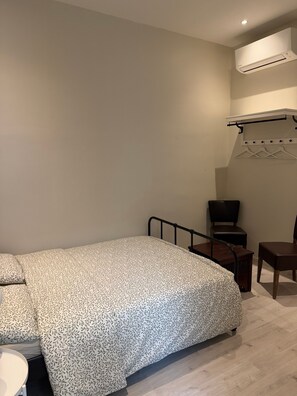 A bedroom with a bed, a chair, a small table, and an air conditioning unit. - Room with Private Bathroom and Air Conditioning – Cagnes-sur-Mer (Cagnes-sur-Mer)