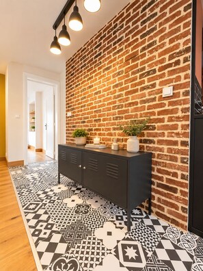 A hallway with a brick wall, a black cabinet, and patterned flooring. - New Listing (Chartres)
