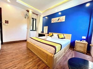 Een hotelkamer met een houten bed, een nachtkastje, een stoel en een blauwe accentmuur.