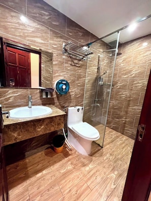 Een badkamer met een marmeren wastafel, toilet en een douchecabine van glas.
