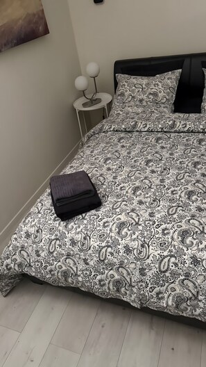 A bedroom with a bed, a bedside table with a lamp, and a wall-mounted artwork. - Room with Private Bathroom and Air Conditioning – Cagnes-sur-Mer (Cagnes-sur-Mer)