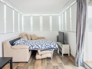 Un dormitorio con cama, escritorio, silla y televisor.