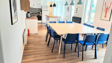 A modern kitchen with a dining area, wooden flooring, and blue chairs.