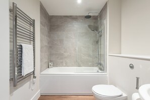 Ein modernes Badezimmer mit einer gläsernen Duschkabine, einer weißen Badewanne und einem WC.