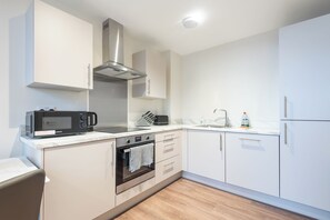 Eine moderne Küche mit integriertem Mikrowellenherd, Backofen und einer Dunstabzugshaube aus Edelstahl.