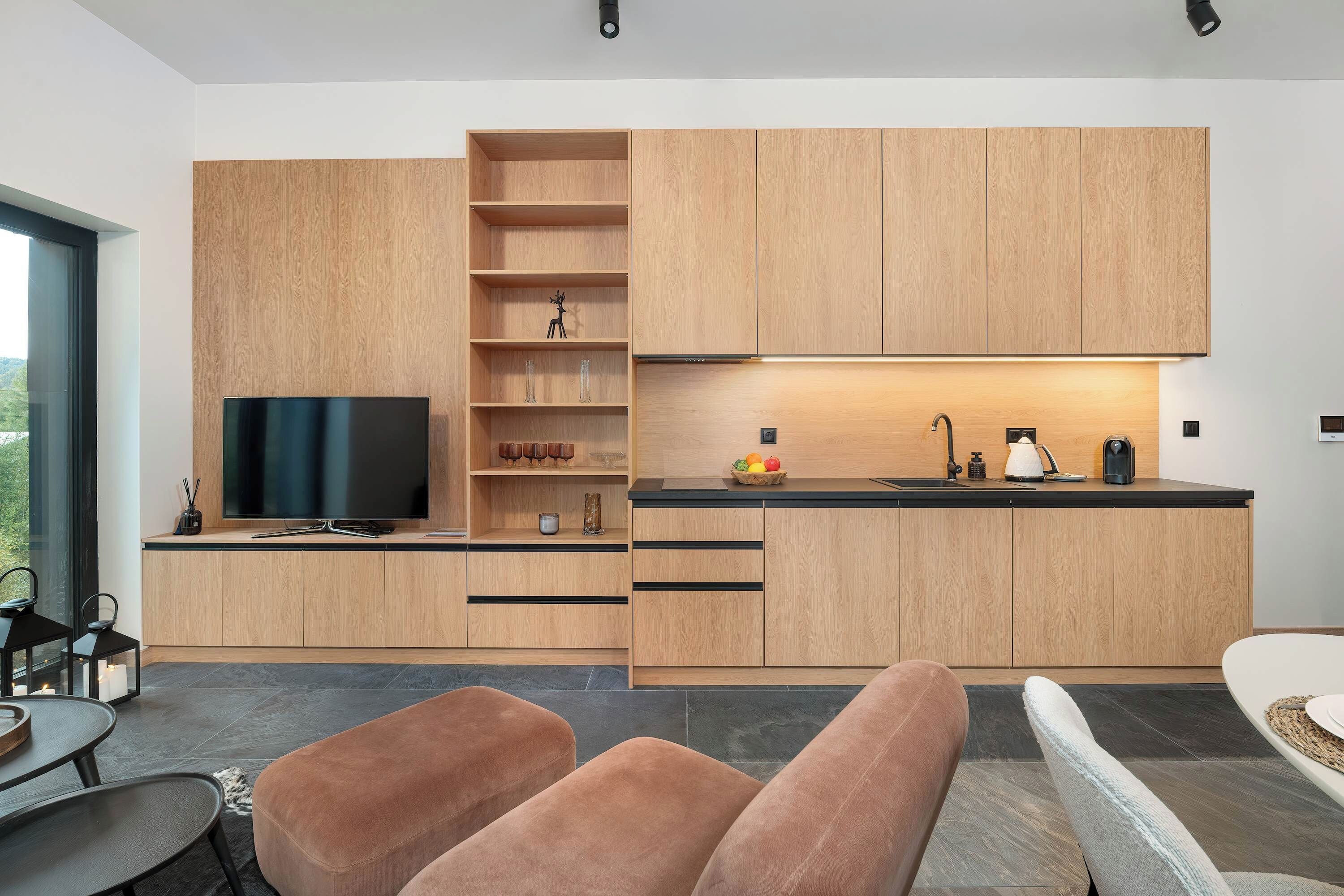 Una cucina moderna con mobili in legno, TV integrata e zona pranzo con tavolo e sedie.