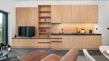 Una cucina moderna con mobili in legno, TV integrata e zona pranzo con tavolo e sedie.