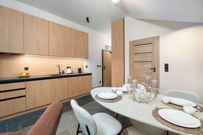 Una cucina moderna con mobili in legno, un piano di lavoro nero e un'area pranzo con un tavolo rotondo per quattro persone.